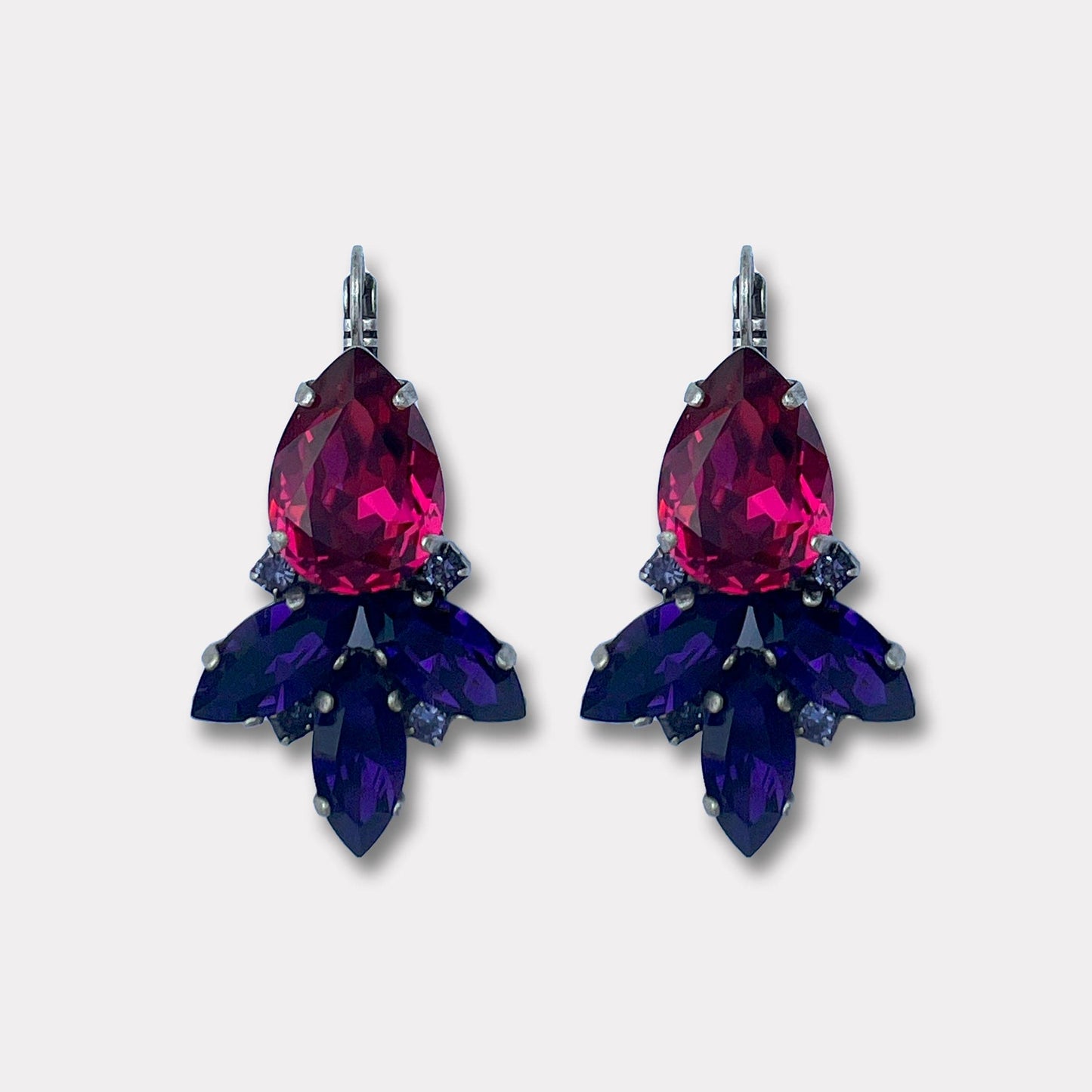 Gaia Fuchsia Silver Farfino Oorbellen verkrijgbaar bij Damice, Onder de bekende “drumpelvormige” Swarovski-kristal hangen drie grote en vier kleine kristalletjes voor de extra bijzondere afwerking.