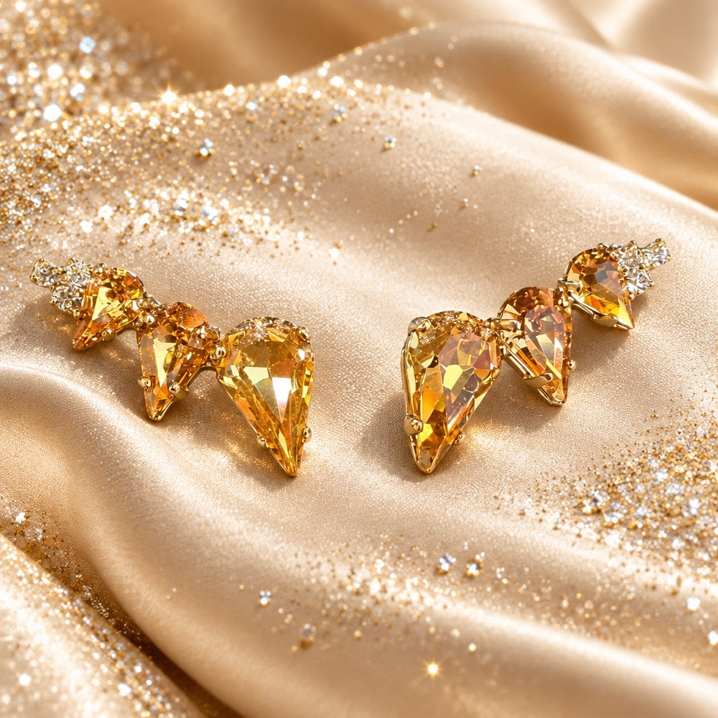 Gouden oorstekers met drie druppelvormige amber kristallen op goudkleurig satijn, statement oorbellen van DAMICE Jewelry